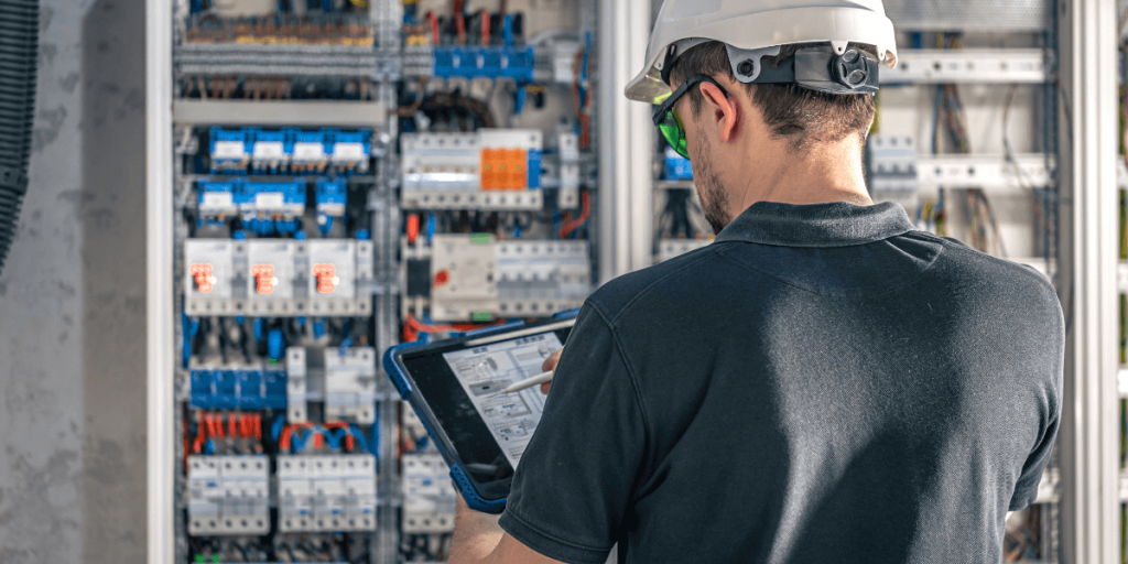 man-electrical-working-switchboard-with-fuses-uses-tablet