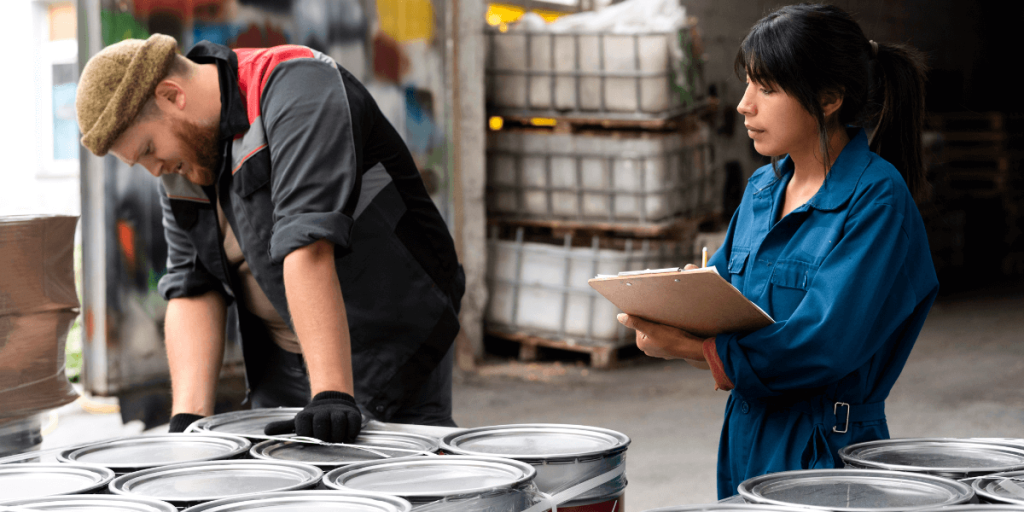 A man and woman stand beside colorful paint cans, discussing their home improvement project.