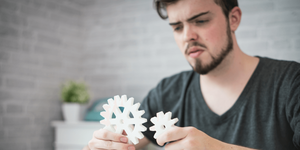 A man holds a white gear in his hands, showcasing its intricate design and functionality.