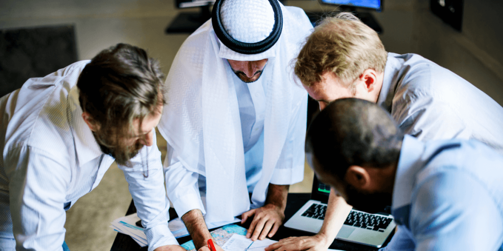 Four men in business suits reviewing documents together in a professional setting.
