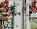 A man operates a machine inside a greenhouse, surrounded by plants and natural light.