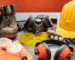 A collection of safety equipment: hard hat, gloves, safety glasses, and boots arranged on a surface.