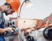 A man wearing an orange hard hat operates a machine, focused on his task in a work environment.