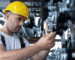 A man wearing a hard hat operates a machine, focused on his task in a work environment.