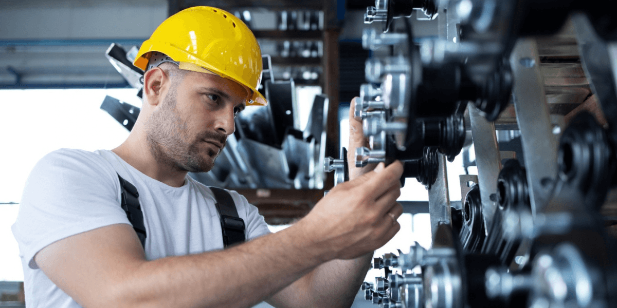 A man wearing a hard hat operates a machine, focused on his task in a work environment.